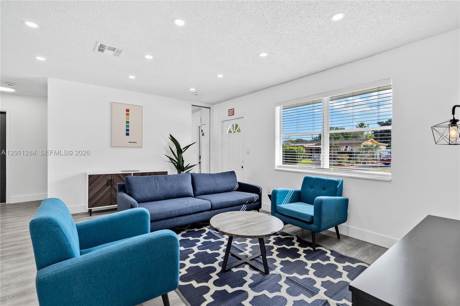 A living room features a blue sofa, two armchairs, a patterned rug, and recessed lighting — 7471 Hope St, Hollywood FL 33024, HOLLYWOOD, FL