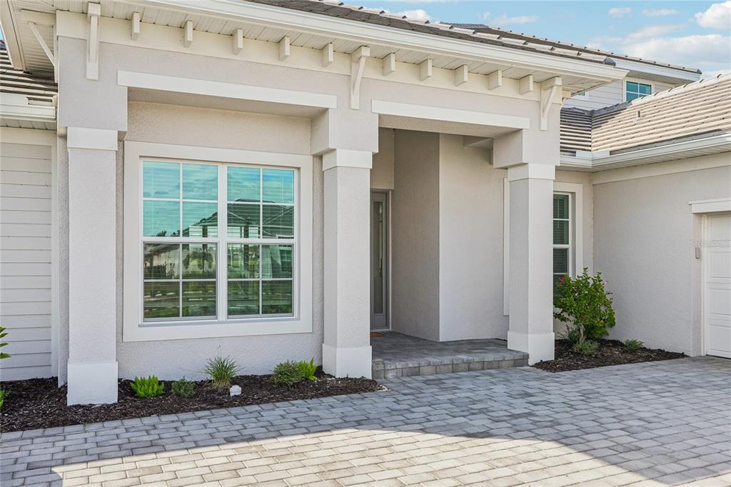 A paved driveway leads to the covered entryway of a light-colored stucco house — 15010 LONGS LANE, PUNTA GORDA, FL