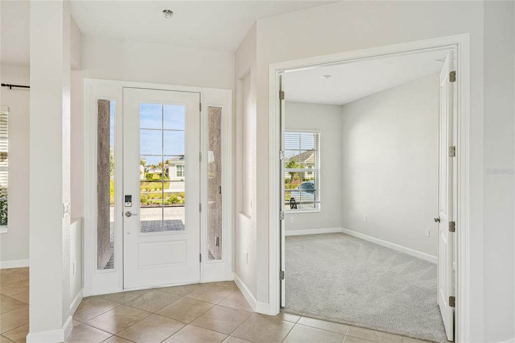 An entryway with tile flooring leads to a front door and a carpeted office space — 15010 LONGS LANE, PUNTA GORDA, FL