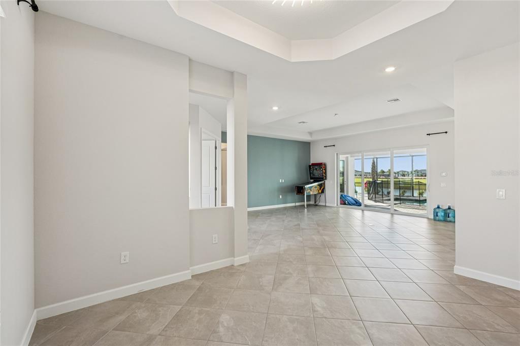 A spacious room with tile flooring, a tray ceiling, and a sliding glass door view — 15010 LONGS LANE, PUNTA GORDA, FL