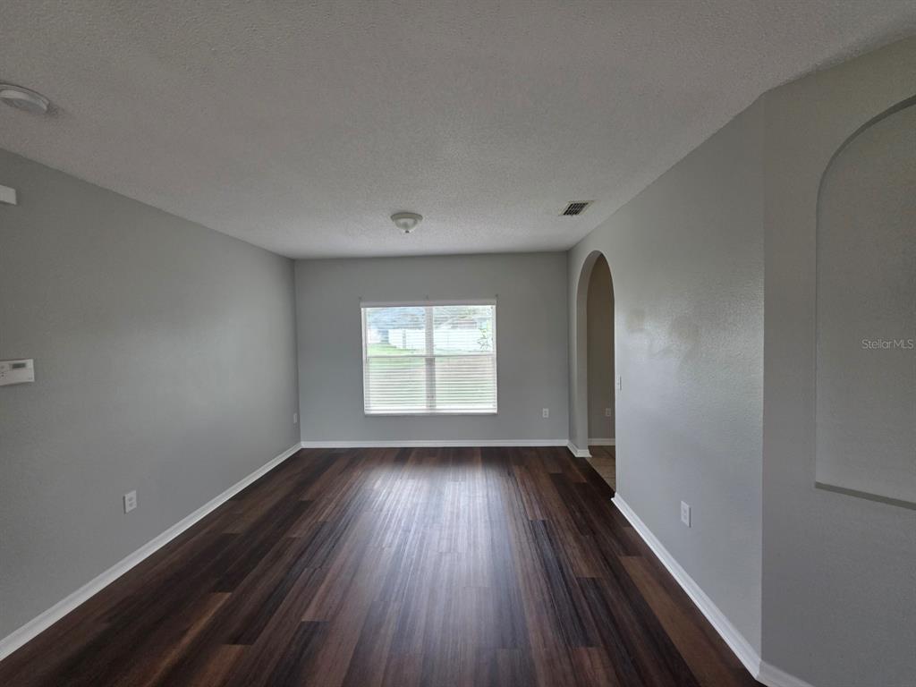 An empty room with gray walls, dark wood-look flooring, and a single window — 579 KILIMANJARO DRIVE, KISSIMMEE, FL