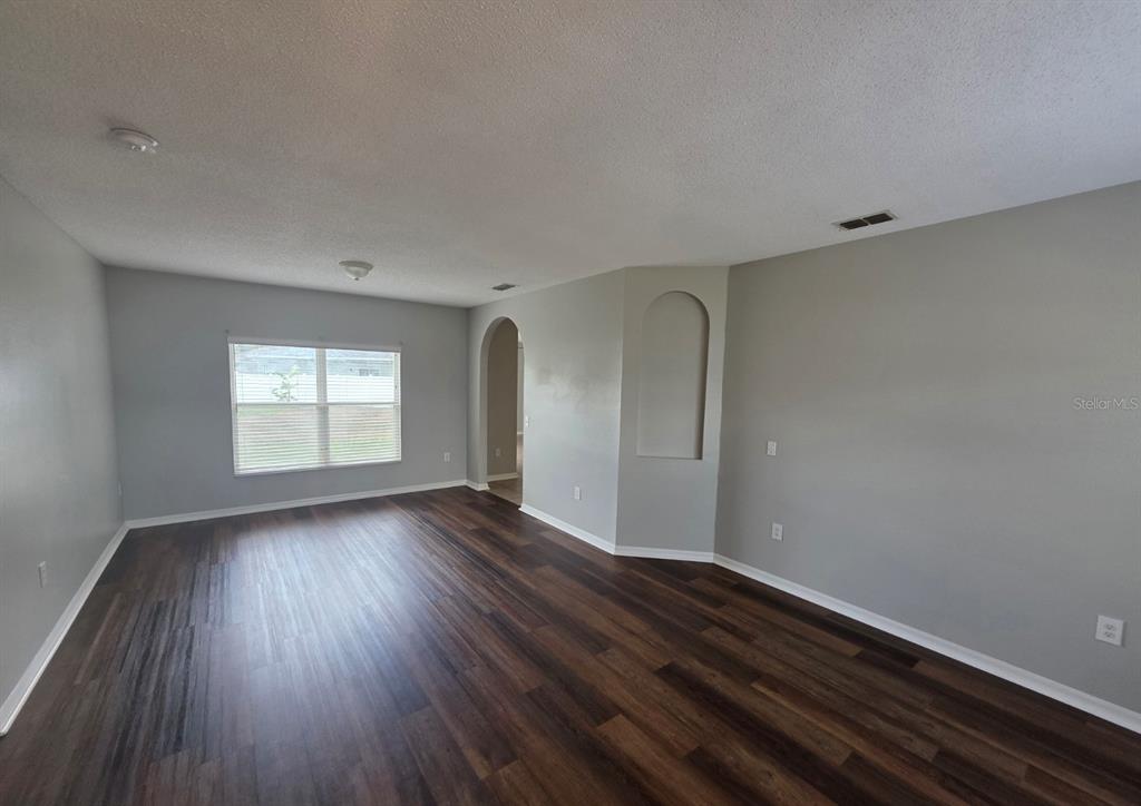 An empty room with gray walls, dark wood-look flooring, and an arched wall niche — 579 KILIMANJARO DRIVE, KISSIMMEE, FL