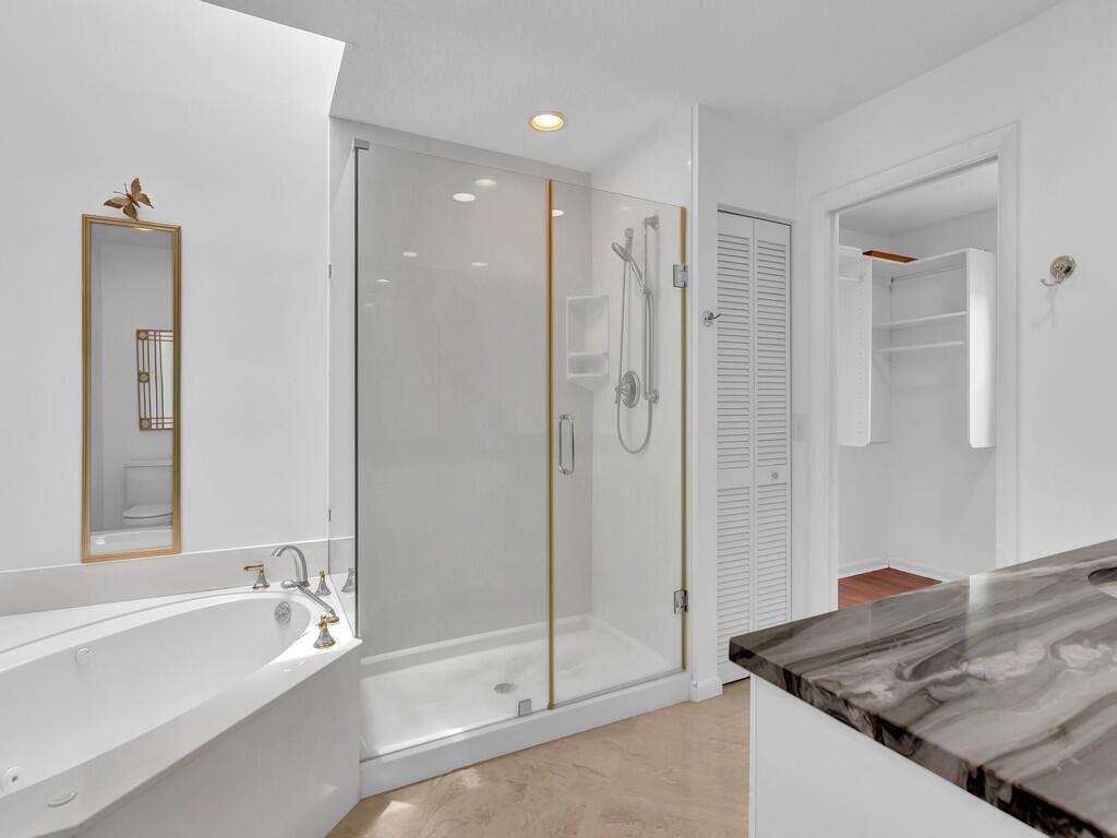 A bathroom features a soaking tub, a glass-enclosed shower with gold trim, and marble countertops — 725 4th Avenue SW, Vero Beach FL 32962, VERO BEACH, FL