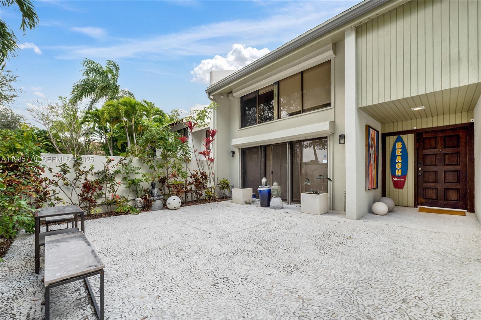 A paved courtyard leads to the entrance of a two-story home with tropical landscaping — 7075 SW 67th Ave # 14, South Miami FL 33143, SOUTH MIAMI, FL
