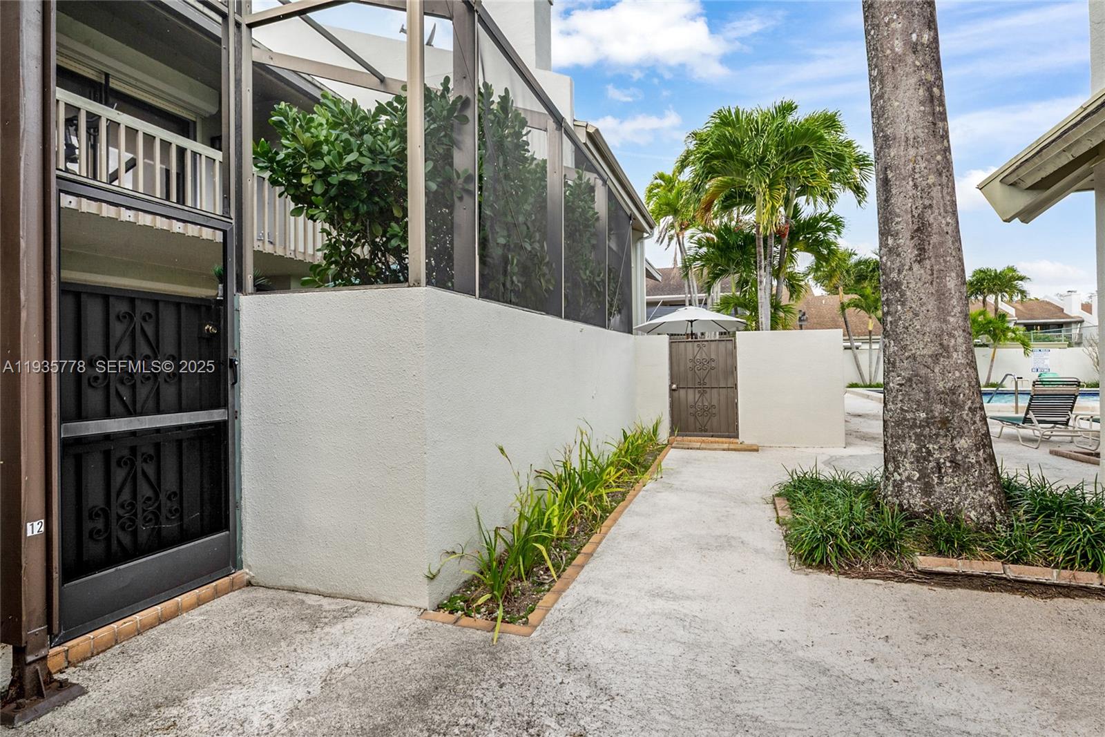 A concrete walkway leads past a screened patio and a gate toward a swimming pool — 7075 SW 67th Ave # 14, South Miami FL 33143, SOUTH MIAMI, FL