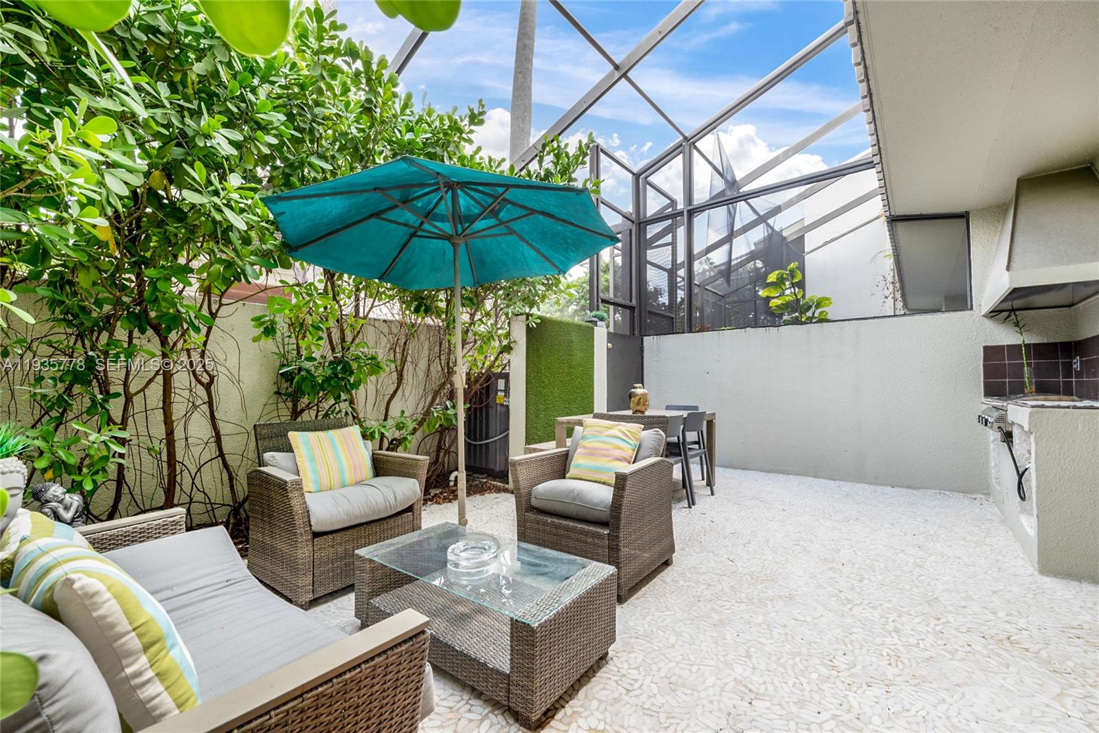 An outdoor patio features wicker furniture, a teal umbrella, and a built-in grill area — 7075 SW 67th Ave # 14, South Miami FL 33143, SOUTH MIAMI, FL