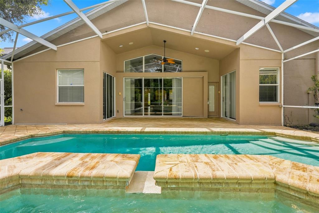 A single-story house with a tan stucco exterior, a two-car garage, and a columned entryway — 27417 SILVER THATCH DRIVE, WESLEY CHAPEL, FL