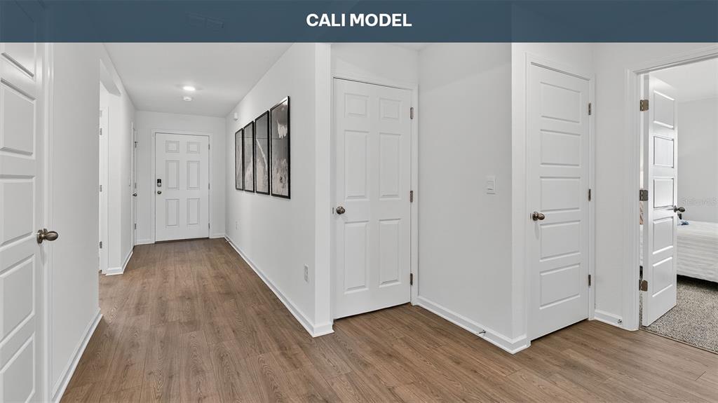A hallway with wood-look flooring leads to a front door and several interior doors — 73 SAWDUST LANE, PALM COAST, FL
