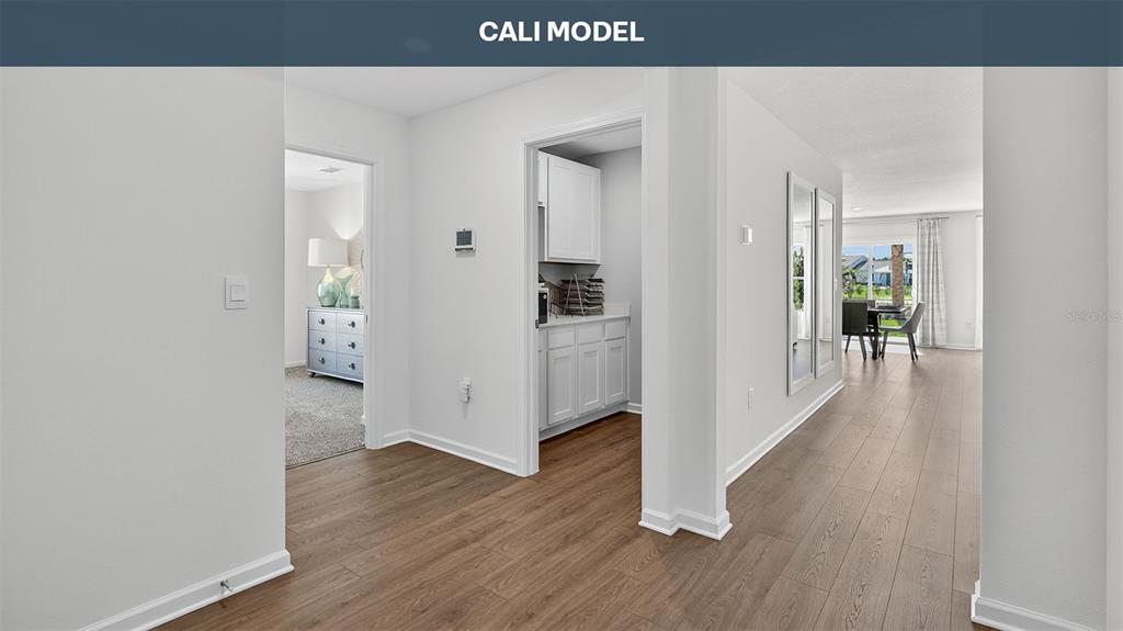 A hallway with wood-look flooring leads to a kitchen, a bedroom, and a dining area — 73 SAWDUST LANE, PALM COAST, FL