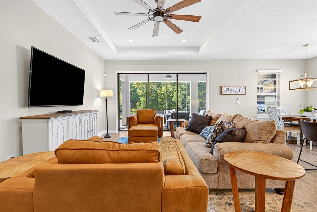 A living room features a large sectional sofa, a television, and sliding glass doors — 10924 WICKER PARK PLACE, PALMETTO, FL