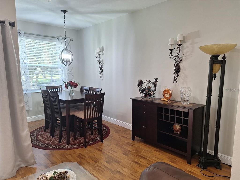 A dining room features a dark wood table, chairs, a matching sideboard, and wall sconces — 3661 PARKRIDGE CIRCLE UNIT 9-104, SARASOTA, FL