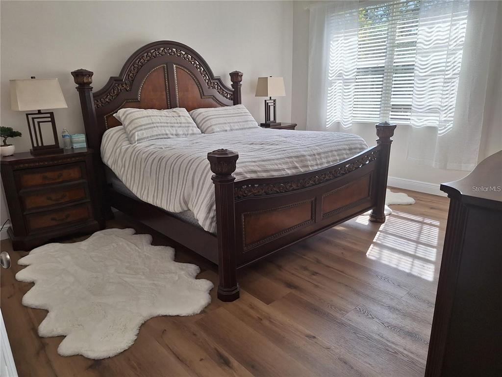 A bedroom features a dark wood bed frame, two nightstands, and light wood flooring — 3661 PARKRIDGE CIRCLE UNIT 9-104, SARASOTA, FL