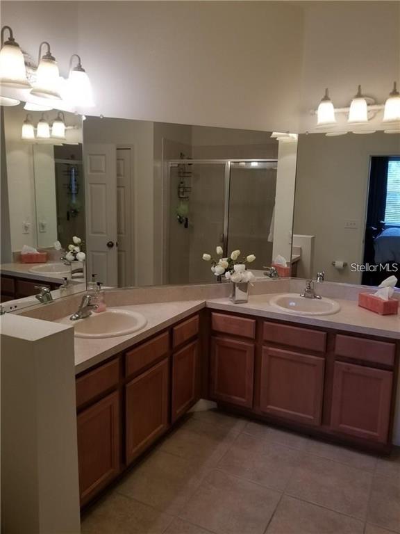 A bathroom features a double vanity with wood cabinets, light countertops, and a large mirror — 3661 PARKRIDGE CIRCLE UNIT 9-104, SARASOTA, FL