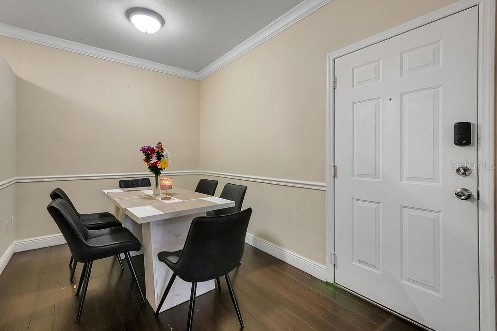 A dining area features a white table with four black chairs on dark wood floors — 3307 S KIRKMAN ROAD UNIT 126, ORLANDO, FL