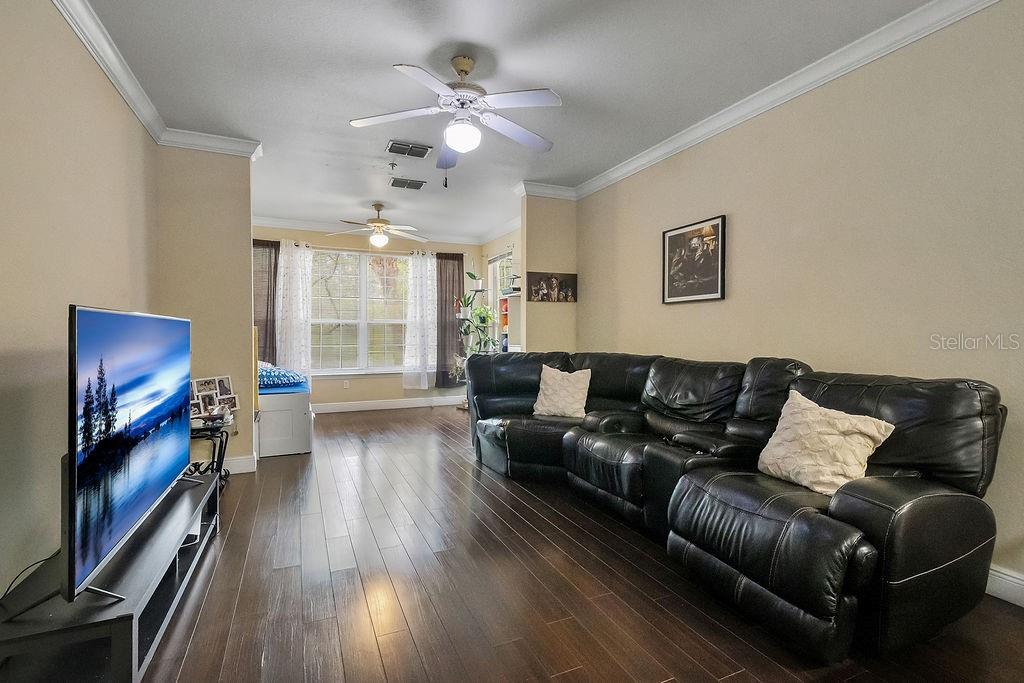 A living room features dark wood flooring, a large black sectional sofa, and a television — 3307 S KIRKMAN ROAD UNIT 126, ORLANDO, FL