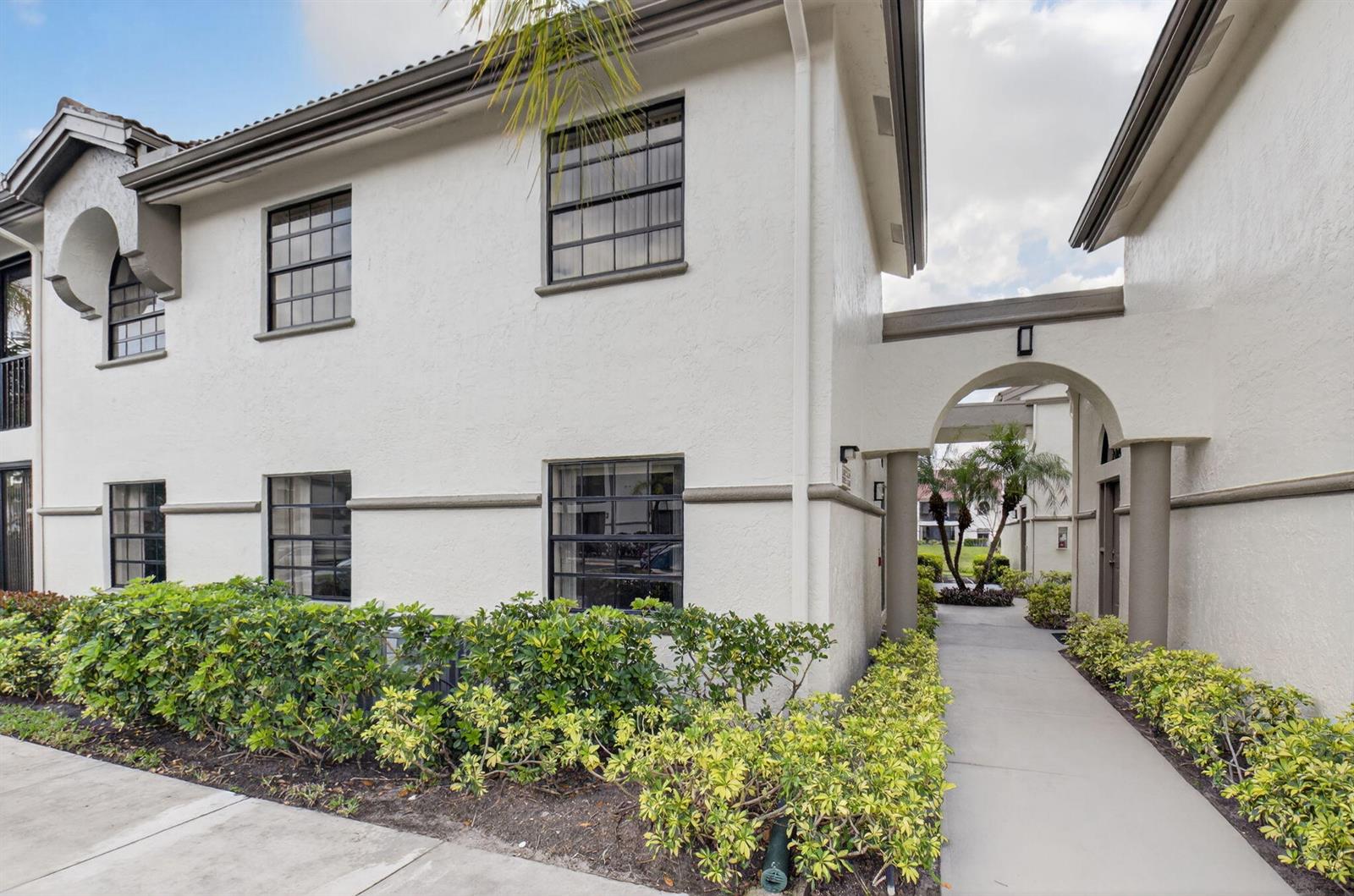 A two-story white stucco building with dark-framed windows and a covered arched walkway — 5226 Europa Drive # H, Boynton Beach FL 33437, BOYNTON BEACH, FL