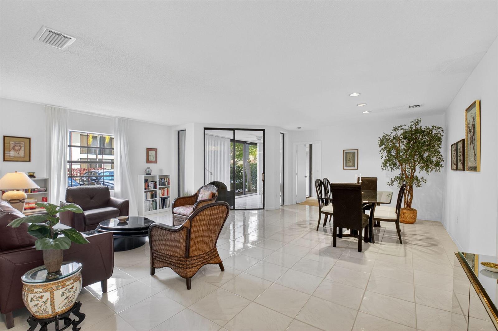 A bright living and dining area features white tile floors, wicker chairs, and glass doors — 5226 Europa Drive # H, Boynton Beach FL 33437, BOYNTON BEACH, FL