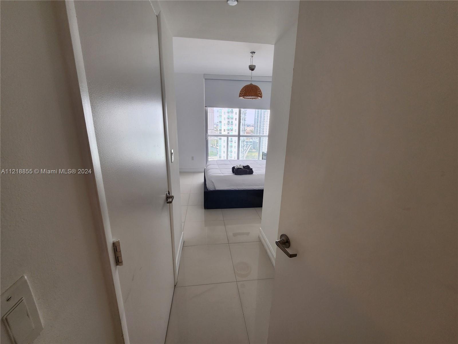 A view through a doorway shows a bedroom with white tile floors and city views — 485 Brickell Ave # 2504, Miami FL 33131, MIAMI, FL