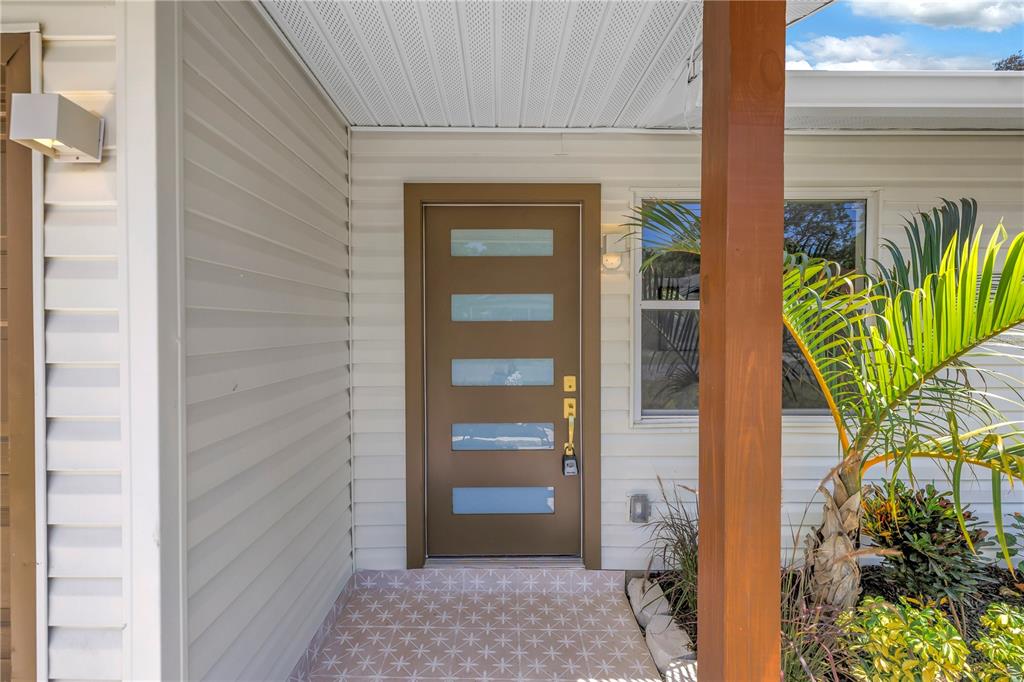 A brown front door with five horizontal glass panels sits on a covered porch — 1221 36TH TERRACE N, ST PETERSBURG, FL