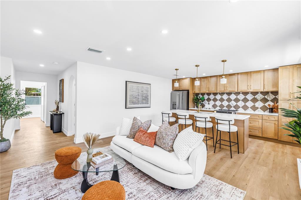 A bright living room and kitchen area with light wood floors and a white sofa — 1221 36TH TERRACE N, ST PETERSBURG, FL
