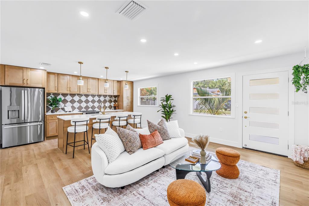 A modern open-concept kitchen and living room featuring light wood flooring and white cabinetry — 1221 36TH TERRACE N, ST PETERSBURG, FL