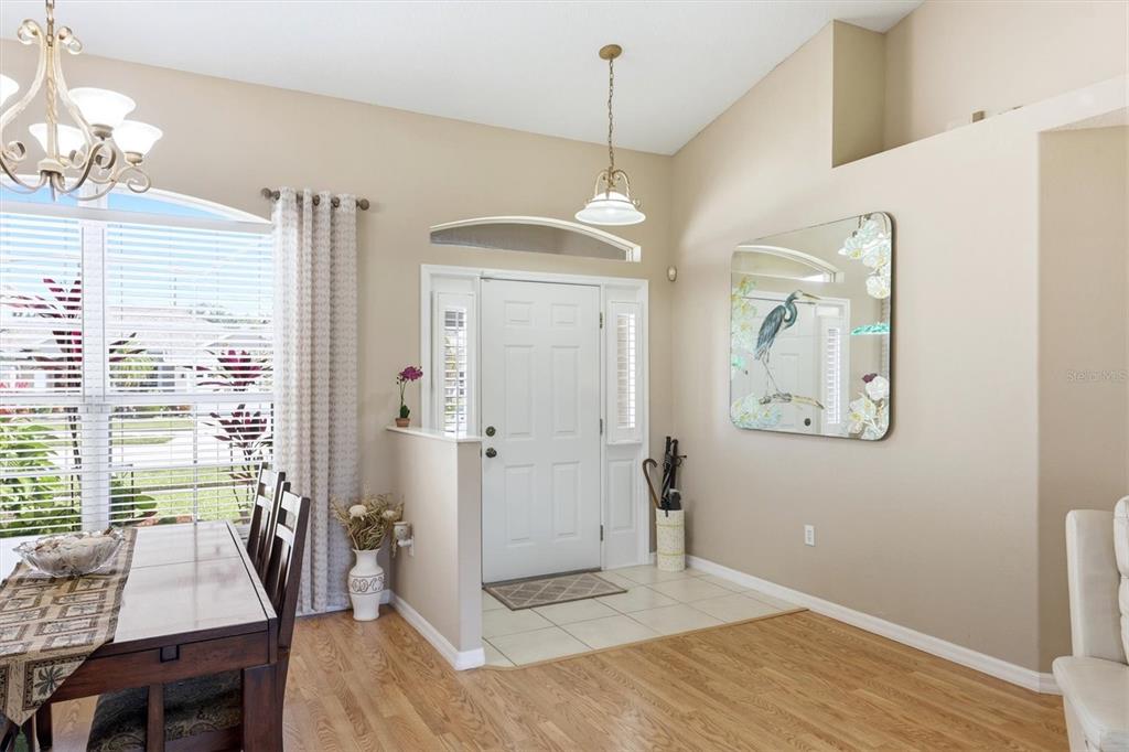An entryway with a white door, tile flooring, and a mirror, adjacent to a dining area — 3220 45TH AVENUE E, BRADENTON, FL