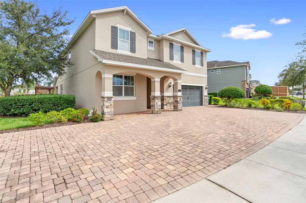 A two-story suburban house with a paved driveway, stone-accented columns, and a garage — 7721 FAIRFAX DRIVE, KISSIMMEE, FL