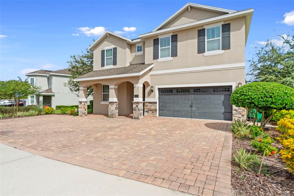 A two-story house with a paved driveway, stone-accented porch, and a dark gray garage door — 7721 FAIRFAX DRIVE, KISSIMMEE, FL