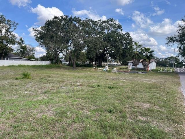 A vacant, grassy lot features several large trees and a small building in the background — 7502 N 40TH STREET, TAMPA, FL