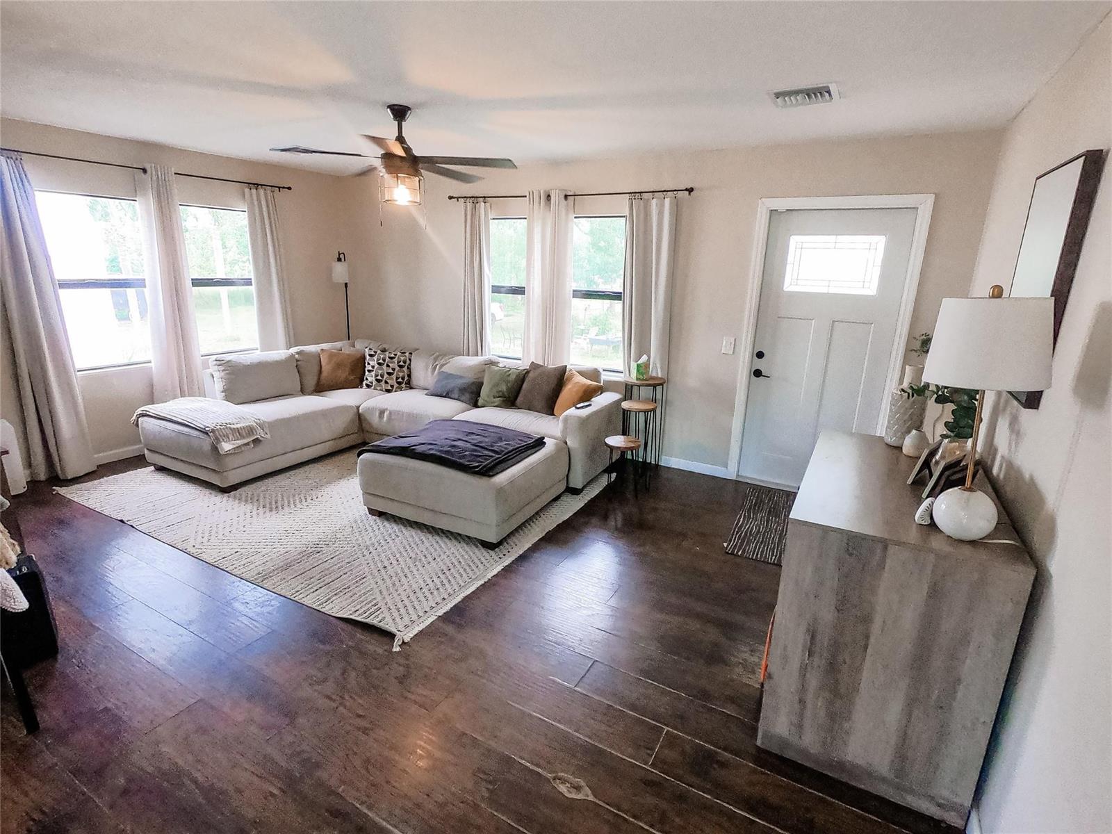 A living room features a sectional sofa, a large area rug, and dark wood flooring — 16140 E Preakness Drive, Loxahatchee FL 33470, LOXAHATCHEE, FL