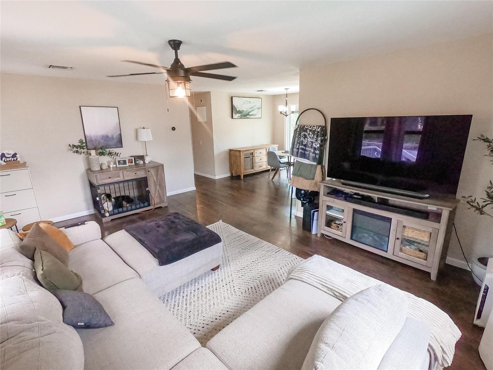 A living room features a sectional sofa, a television on a media console, and wood flooring — 16140 E Preakness Drive, Loxahatchee FL 33470, LOXAHATCHEE, FL