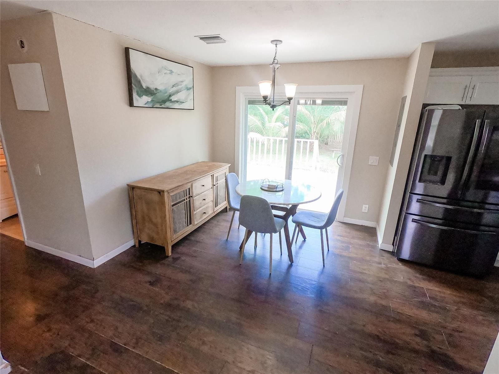 A dining area features a round table, three chairs, a wooden sideboard, and sliding glass doors — 16140 E Preakness Drive, Loxahatchee FL 33470, LOXAHATCHEE, FL