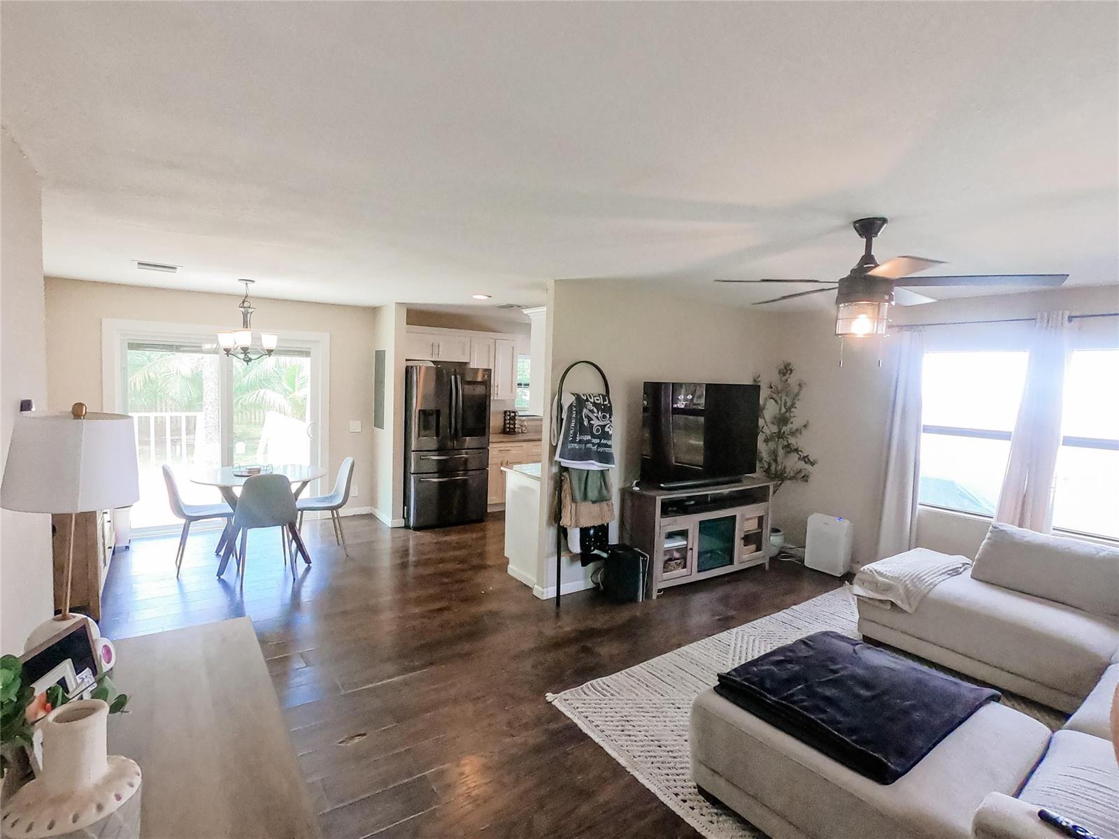 An open-concept living room and dining area feature dark wood floors and a ceiling fan — 16140 E Preakness Drive, Loxahatchee FL 33470, LOXAHATCHEE, FL