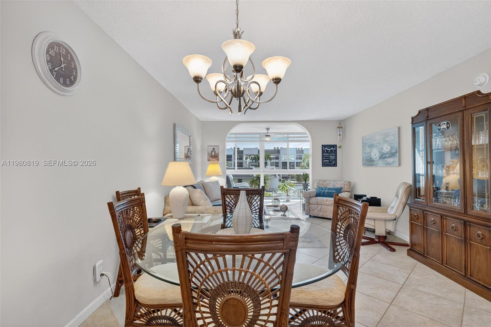 A dining area with a glass table and wicker chairs opens into a living room — 6650 Royal Palm Blvd # 207C, Margate FL 33063, MARGATE, FL