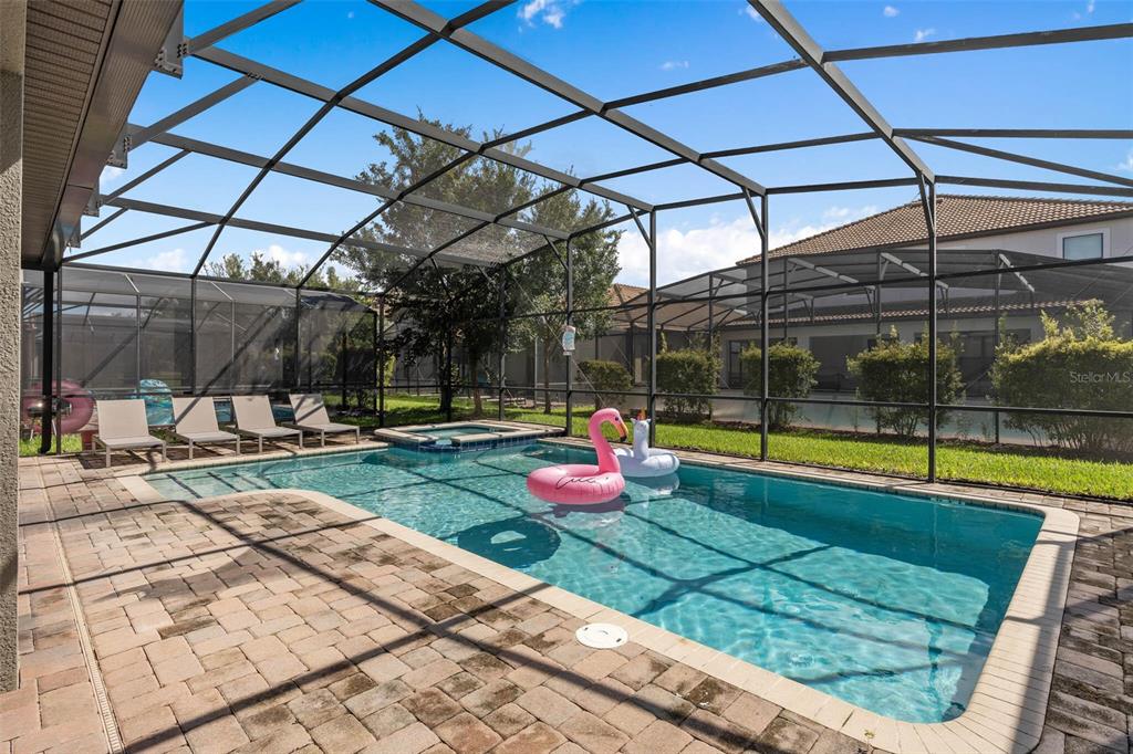A screened-in swimming pool and spa with lounge chairs on a paved patio — 1425 WEXFORD WAY, DAVENPORT, FL
