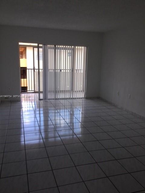 An empty room with white walls, light-colored floor tiles, and a sliding glass balcony door — 1855 W 60th St # 423C, Hialeah FL 33012, HIALEAH, FL