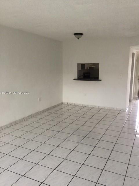 An empty room with white walls, white tiled floors, and a kitchen pass-through window — 1855 W 60th St # 423C, Hialeah FL 33012, HIALEAH, FL