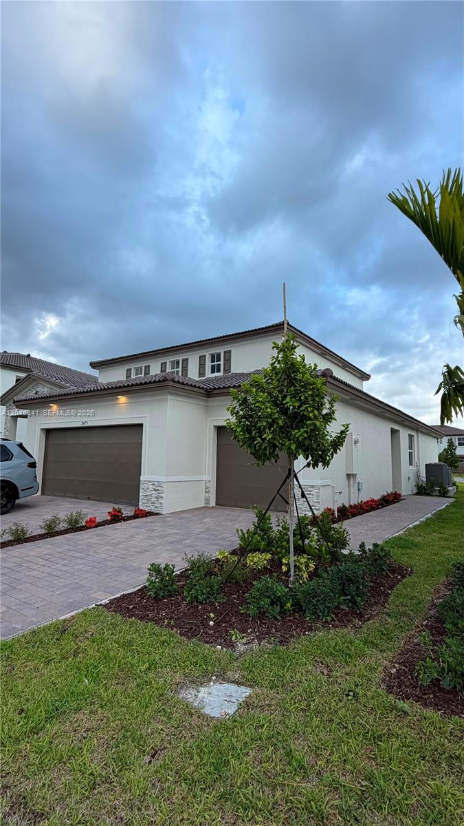 A two-story house with a paved driveway, two garage doors, and a small landscaped garden — 2475 SE 29th Dr, Homestead FL 33035, HOMESTEAD, FL