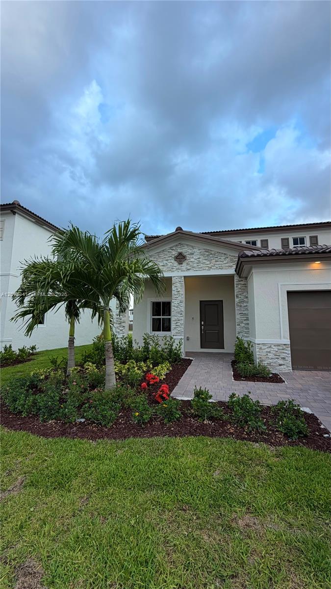 A single-story house exterior features a stone-accented entryway, a paved walkway, and palm trees — 2475 SE 29th Dr, Homestead FL 33035, HOMESTEAD, FL
