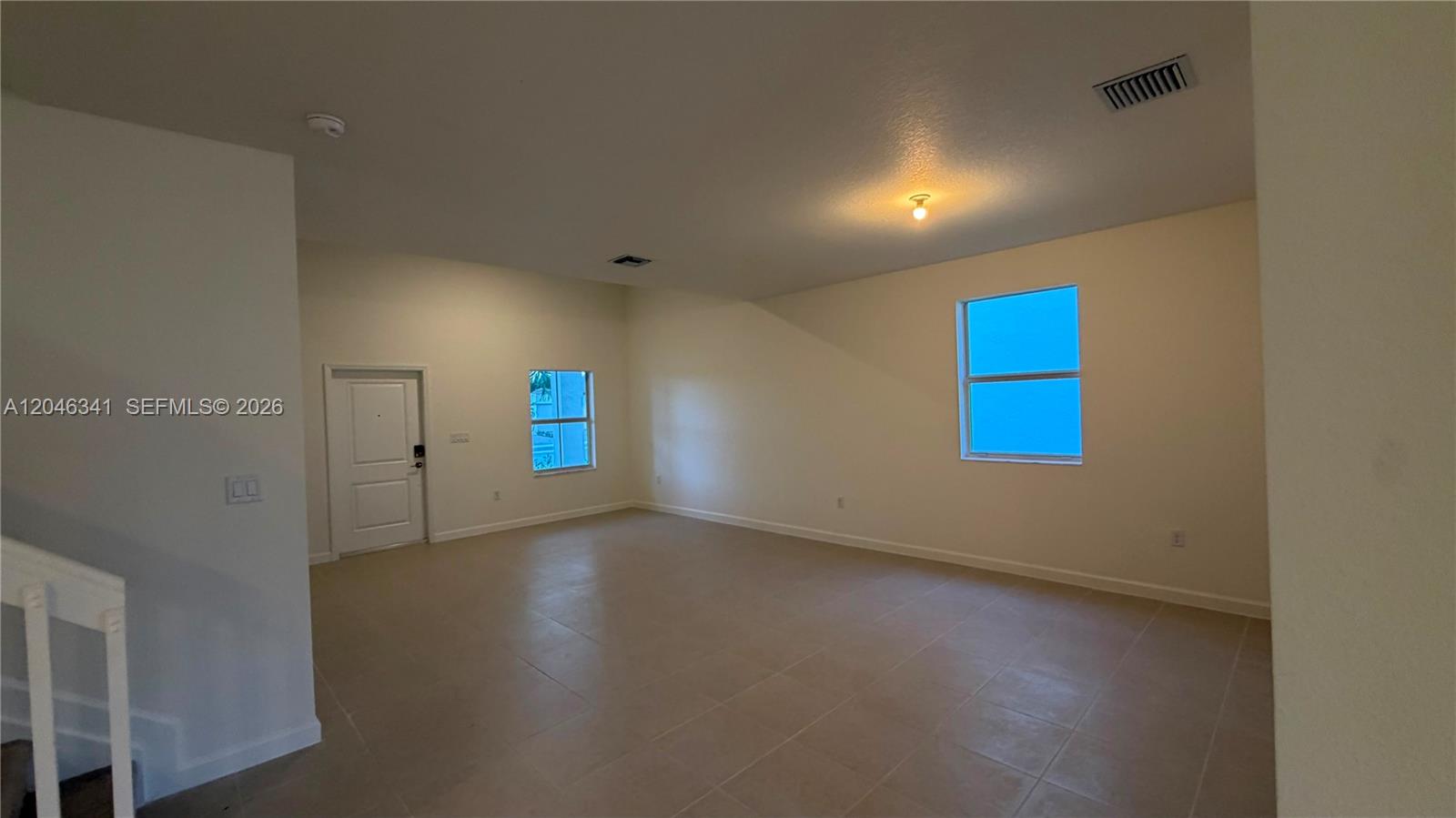 An empty room with light-colored tile flooring, white walls, and two windows — 2475 SE 29th Dr, Homestead FL 33035, HOMESTEAD, FL