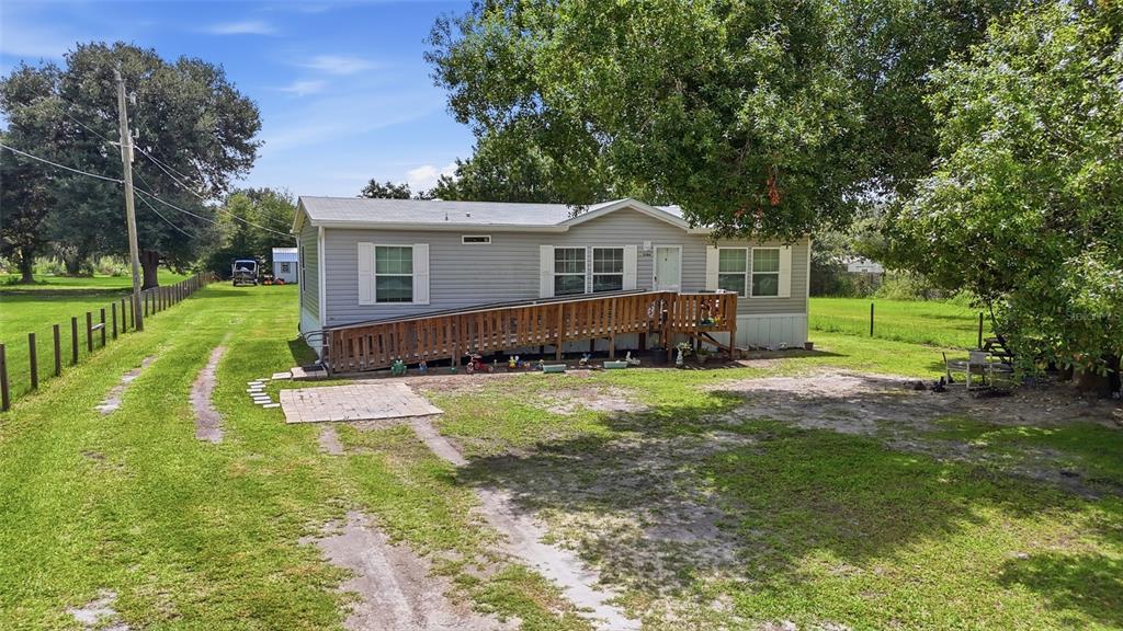 A single-story manufactured home with a wooden wheelchair ramp sits on a grassy lot — 2086 NW GENES LITTLE ACRES AVENUE, ARCADIA, FL