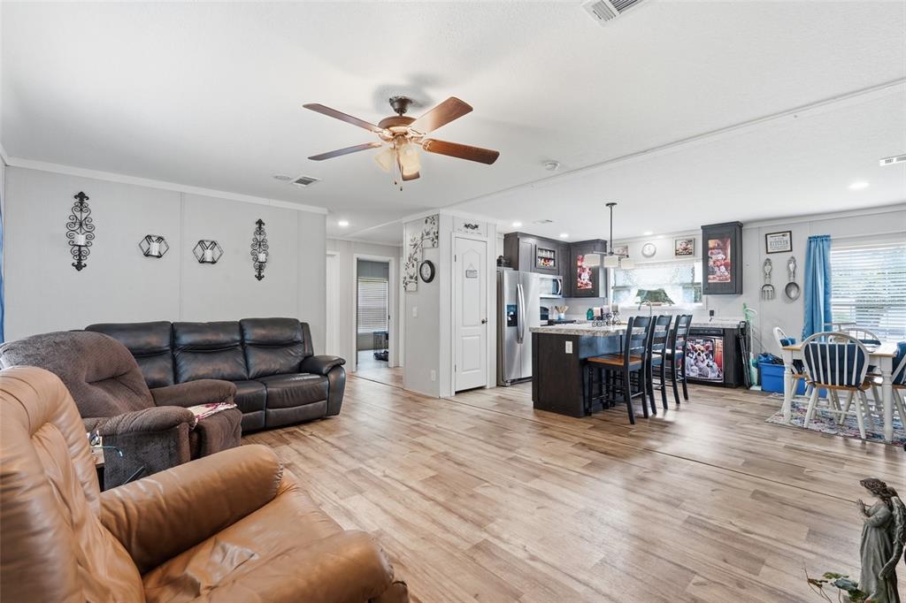 An open-concept living room and kitchen featuring wood-look flooring, dark cabinetry, and a ceiling fan — 2086 NW GENES LITTLE ACRES AVENUE, ARCADIA, FL