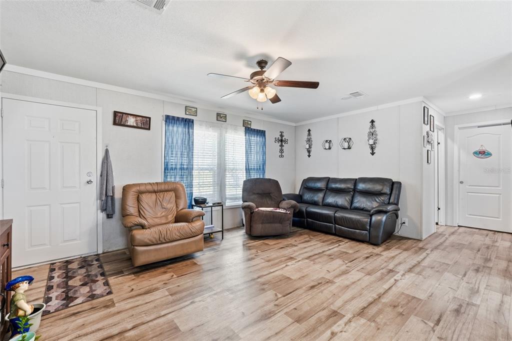 A living room features light wood-look flooring, a ceiling fan, and a leather furniture set — 2086 NW GENES LITTLE ACRES AVENUE, ARCADIA, FL