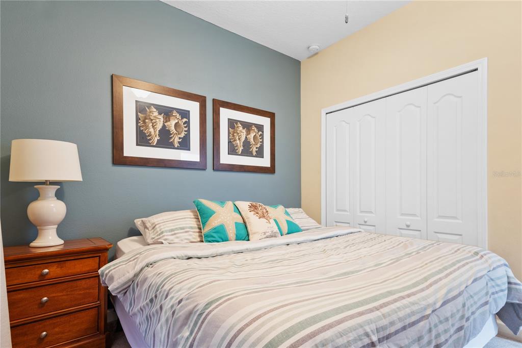 A bedroom features a bed with striped bedding, blue accent wall, and a wooden nightstand — 8966 CAT PALM ROAD, KISSIMMEE, FL
