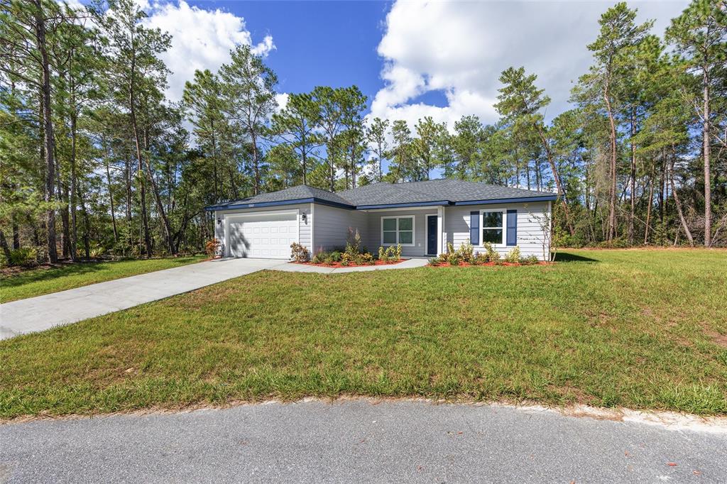 A single-story house with gray siding, a white garage door, and blue shutters — 119 NW REDWOOD DRIVE, DUNNELLON, FL