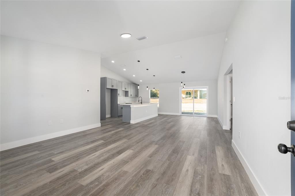 A living room features gray wood-look flooring, a gray sofa, and a wall-mounted television — 119 NW REDWOOD DRIVE, DUNNELLON, FL