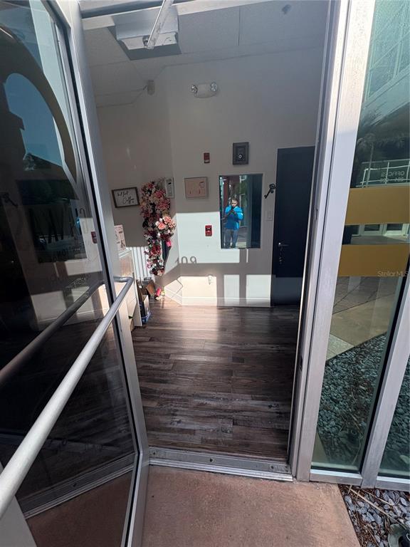 A view through an open glass door into a small office space with wood flooring — 12701 S JOHN YOUNG PARKWAY UNIT 109, ORLANDO, FL