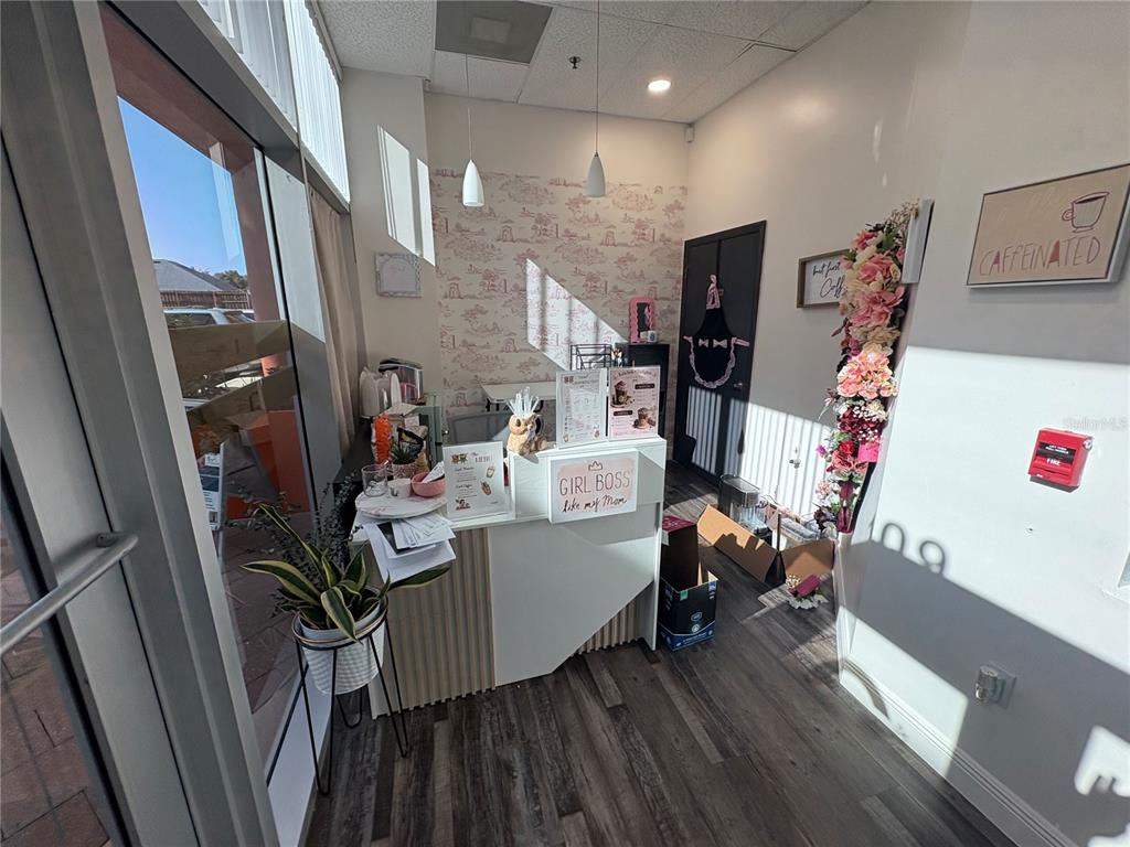 A small commercial reception area features a desk, patterned wallpaper, and a floral wall decoration — 12701 S JOHN YOUNG PARKWAY UNIT 109, ORLANDO, FL
