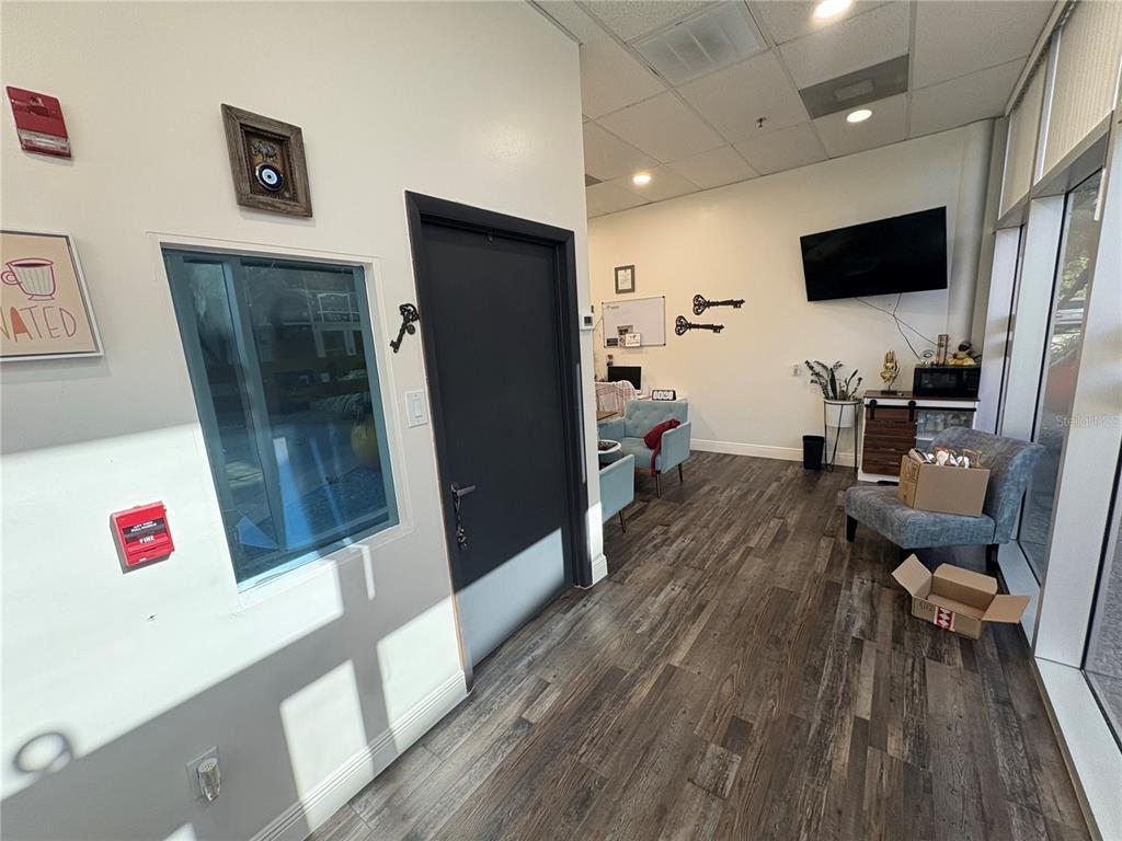 An office interior features a dark door, wood-look flooring, a window, and a television — 12701 S JOHN YOUNG PARKWAY UNIT 109, ORLANDO, FL