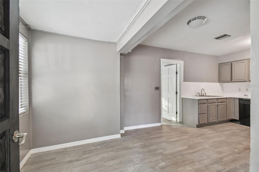 A view of a kitchen and dining area with gray walls and wood-look flooring — 1921 W STATE STREET, TAMPA, FL